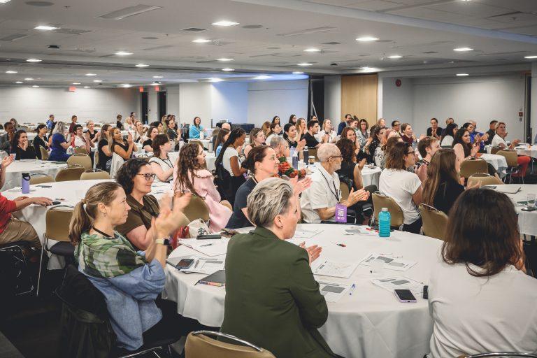Participants seated at round tables applaud a speaker during a plenary session of the 1st International Congress on Safe Sport Research in Québec City.