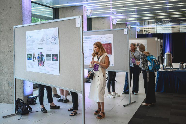 A participant reviews research posters during the 1st International Congress on Safe Sport Research in Québec City, with several displays visible in the exhibition area.