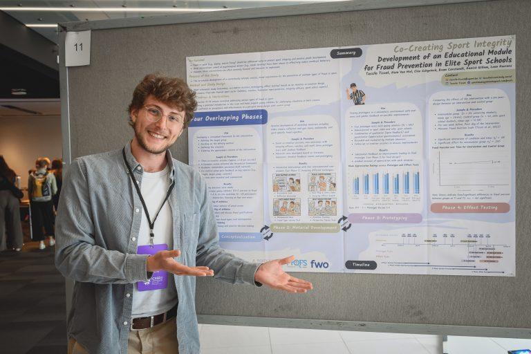 A researcher stands next to a poster presentation explaining findings during the 1st International Congress on Safe Sport Research in Québec City.