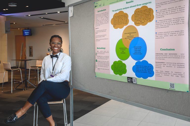 A participant poses beside a research poster on display during the 1st International Congress on Safe Sport Research in Québec City.