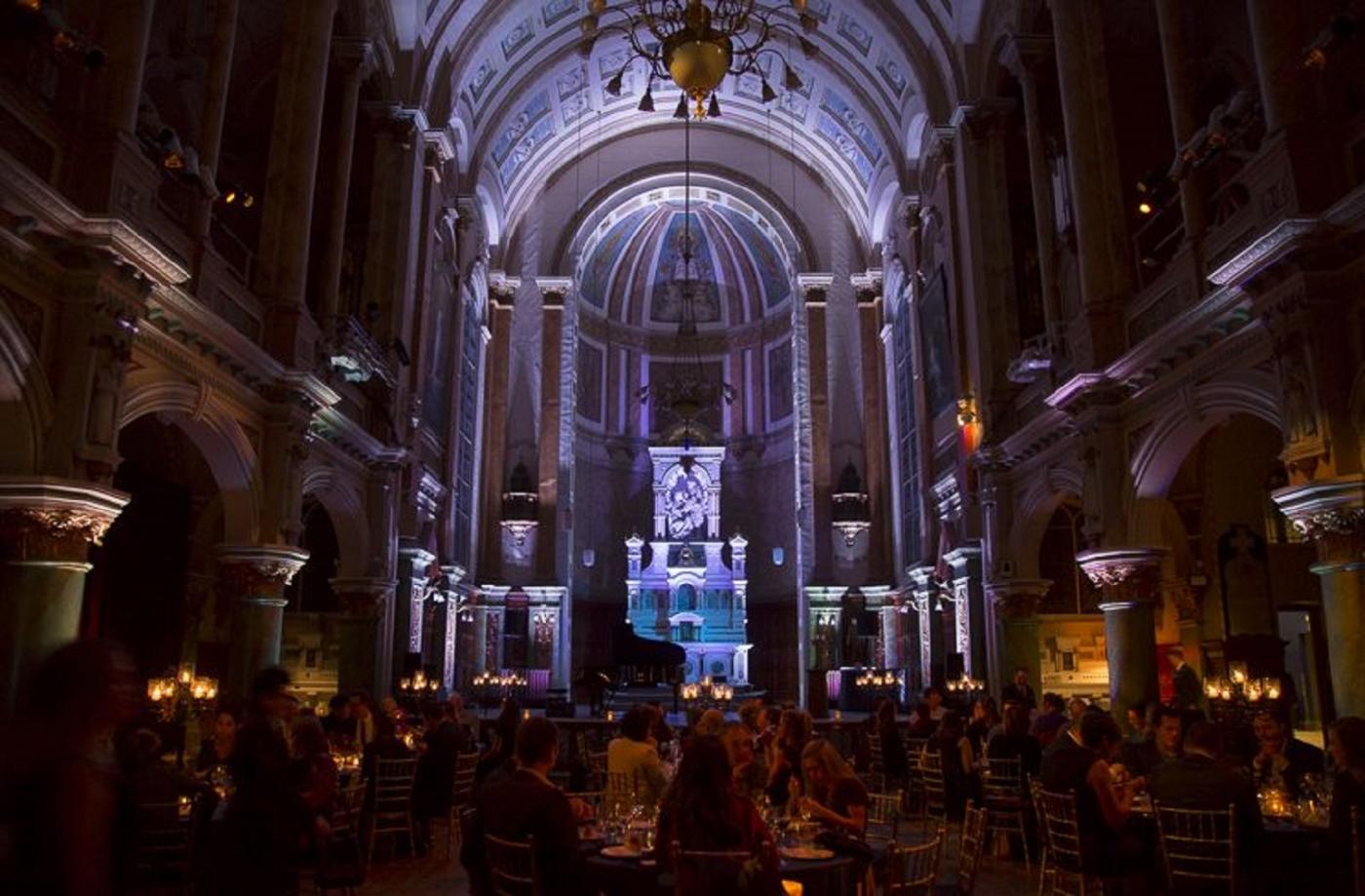 Several people are in the chapel of the Museum of French-speaking America in the evening.