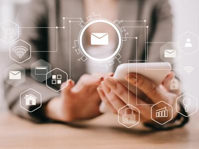 Close-up of a person using a smartphone, with digital email icons representing email marketing and online communication