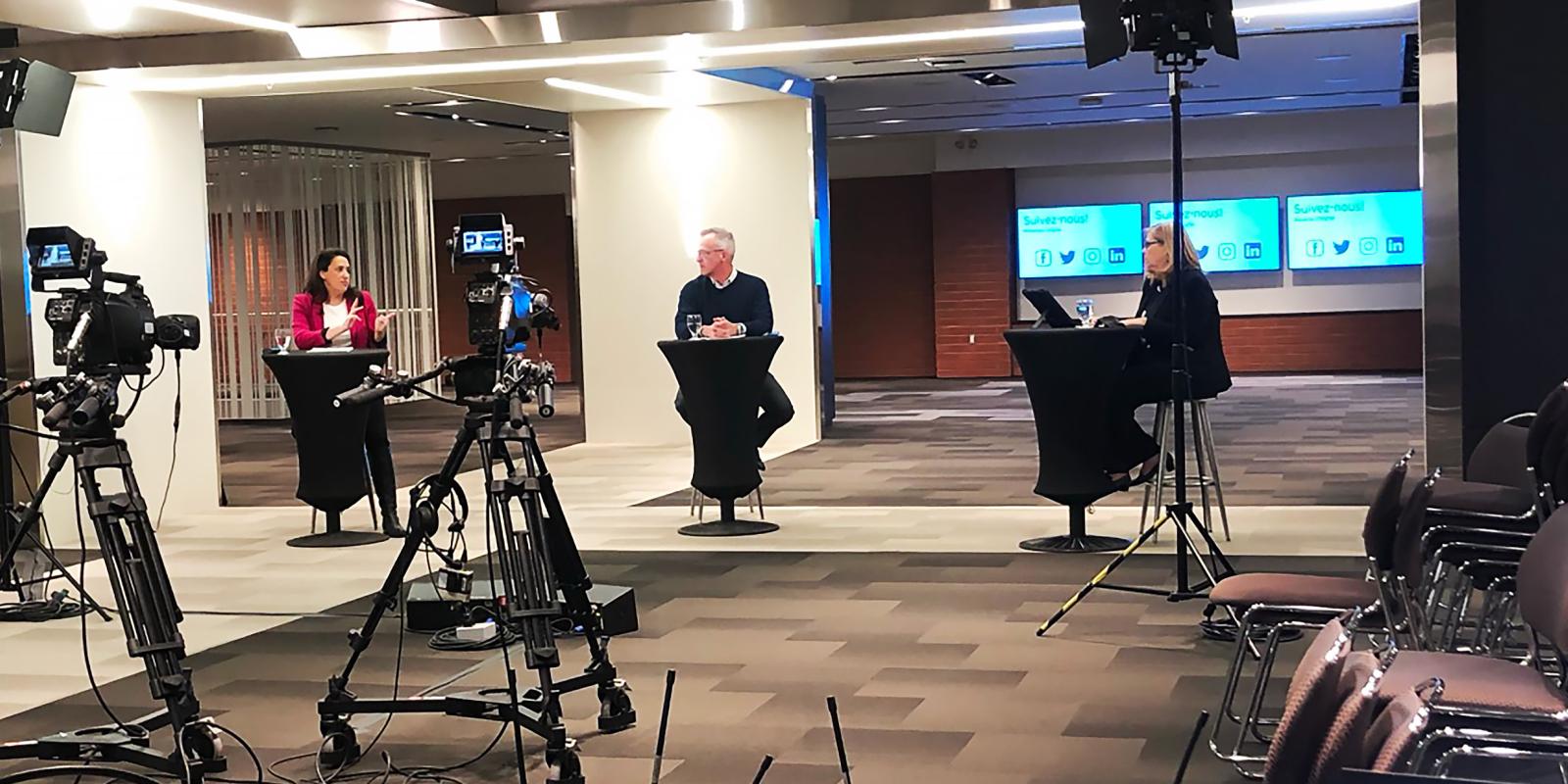 Image de 3 conférenciers animant une discussion lors d'un événement hybride organisé au Centre des congrès de Québec