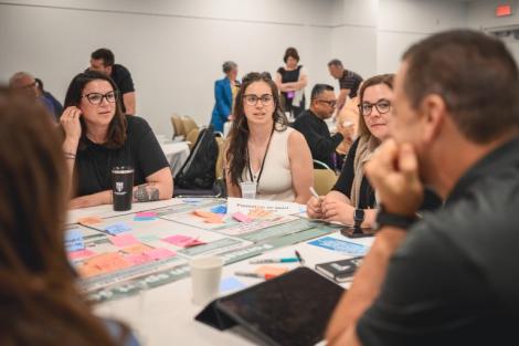 Participants take part in a collaborative workshop during the 1st International Congress on Safe Sport Research in Québec City, exchanging ideas around a table covered with discussion materials.