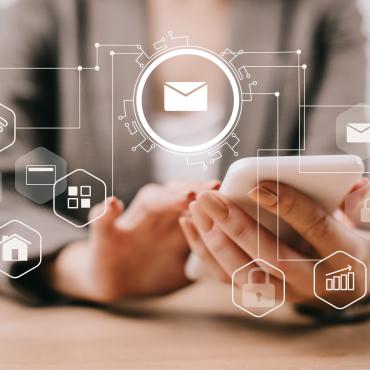 Close-up of a person using a smartphone, with digital email icons representing email marketing and online communication